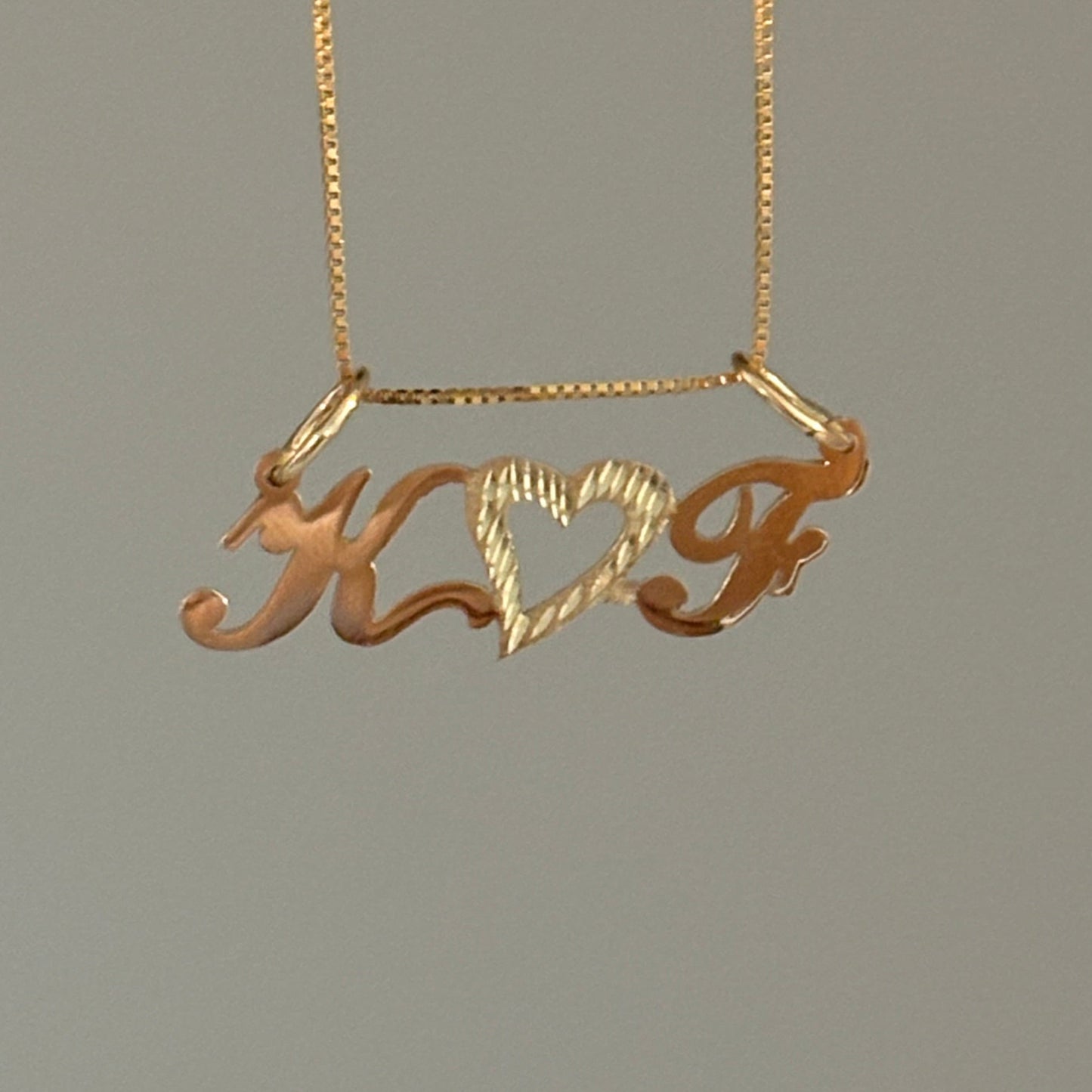 Gold necklace with a decorative pendant on a gray background