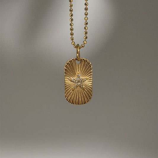 A 14K gold diamond star engine-turned pendant on a gold chain.