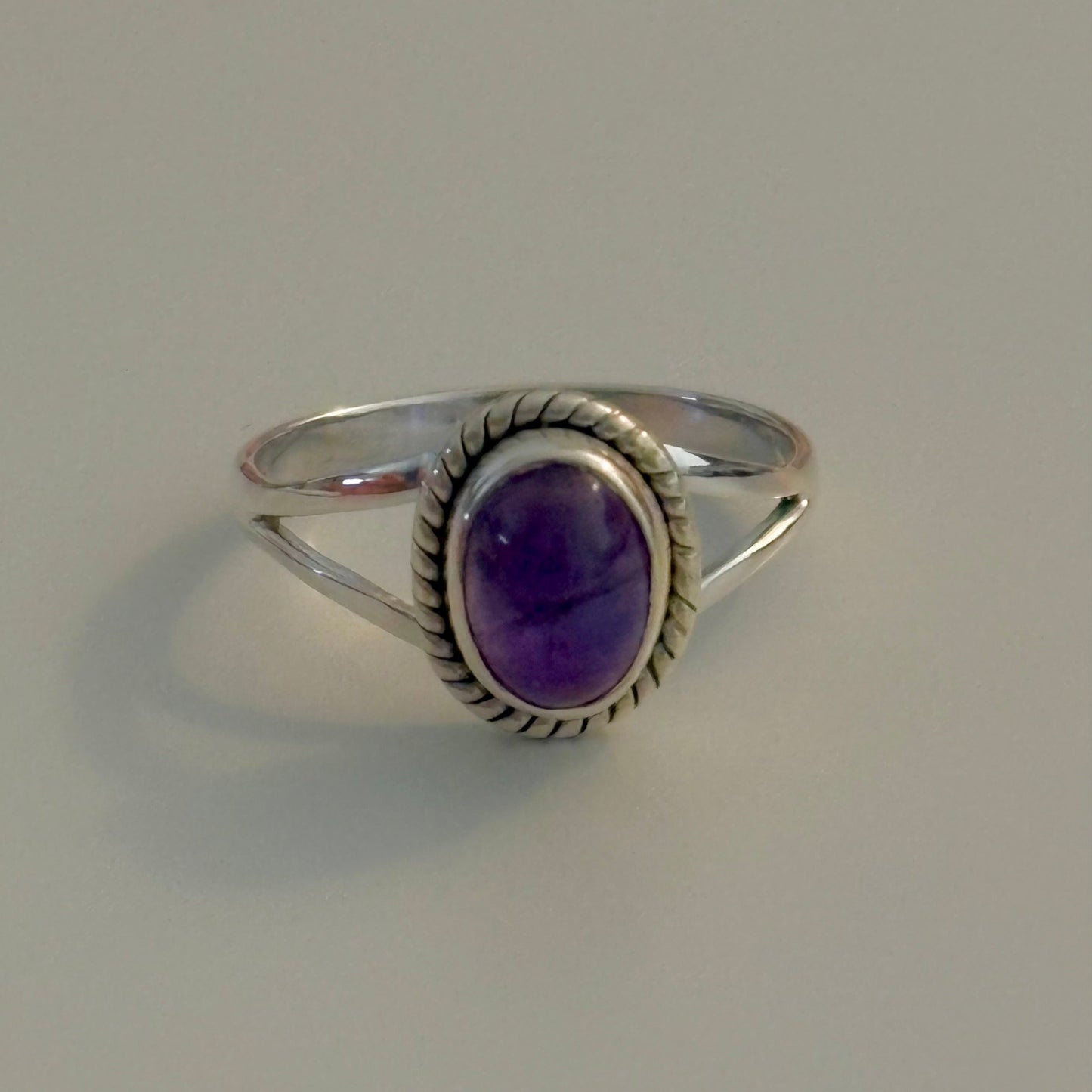 Silver ring with a purple gemstone on a gray background