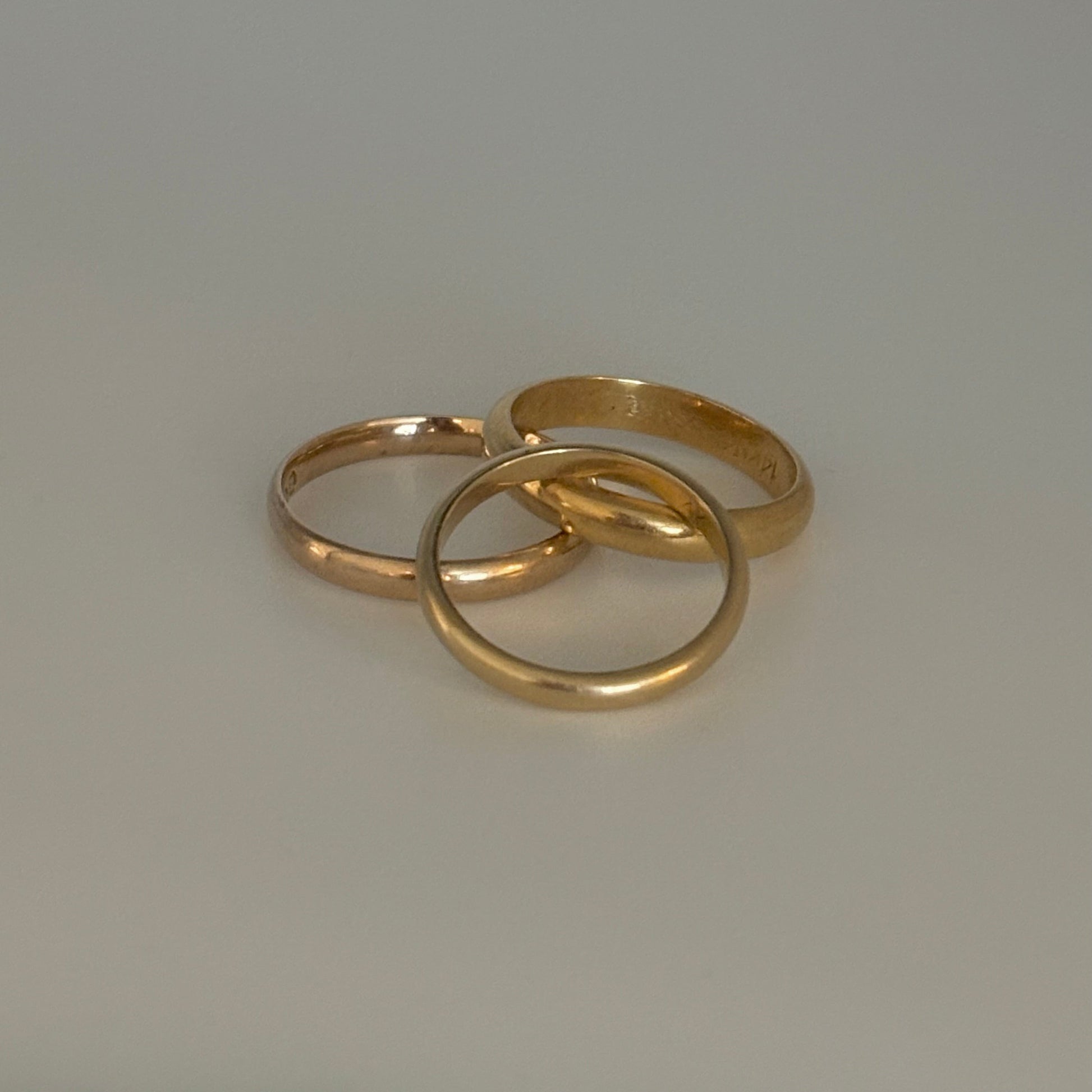 Three gold rings on a light gray background