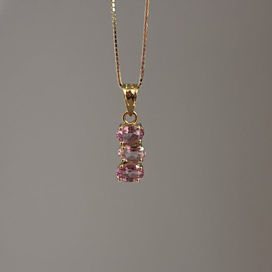 A pink topaz charm with cubic zirconia in a vertical alignment, attached to a gold-colored chain.