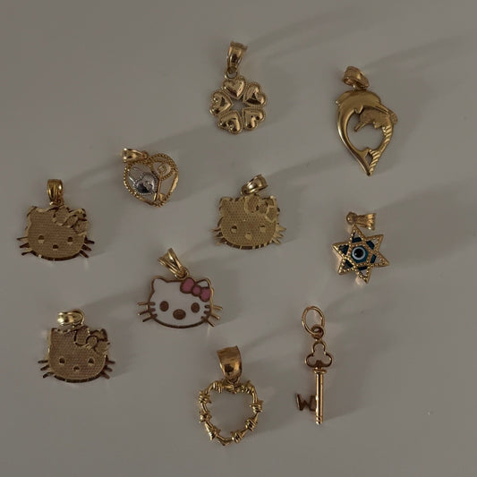 Collection of various gold pendants on a gray background