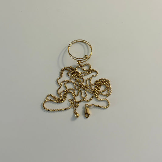 Gold chain keychain on a white surface next to a gold electronic device
