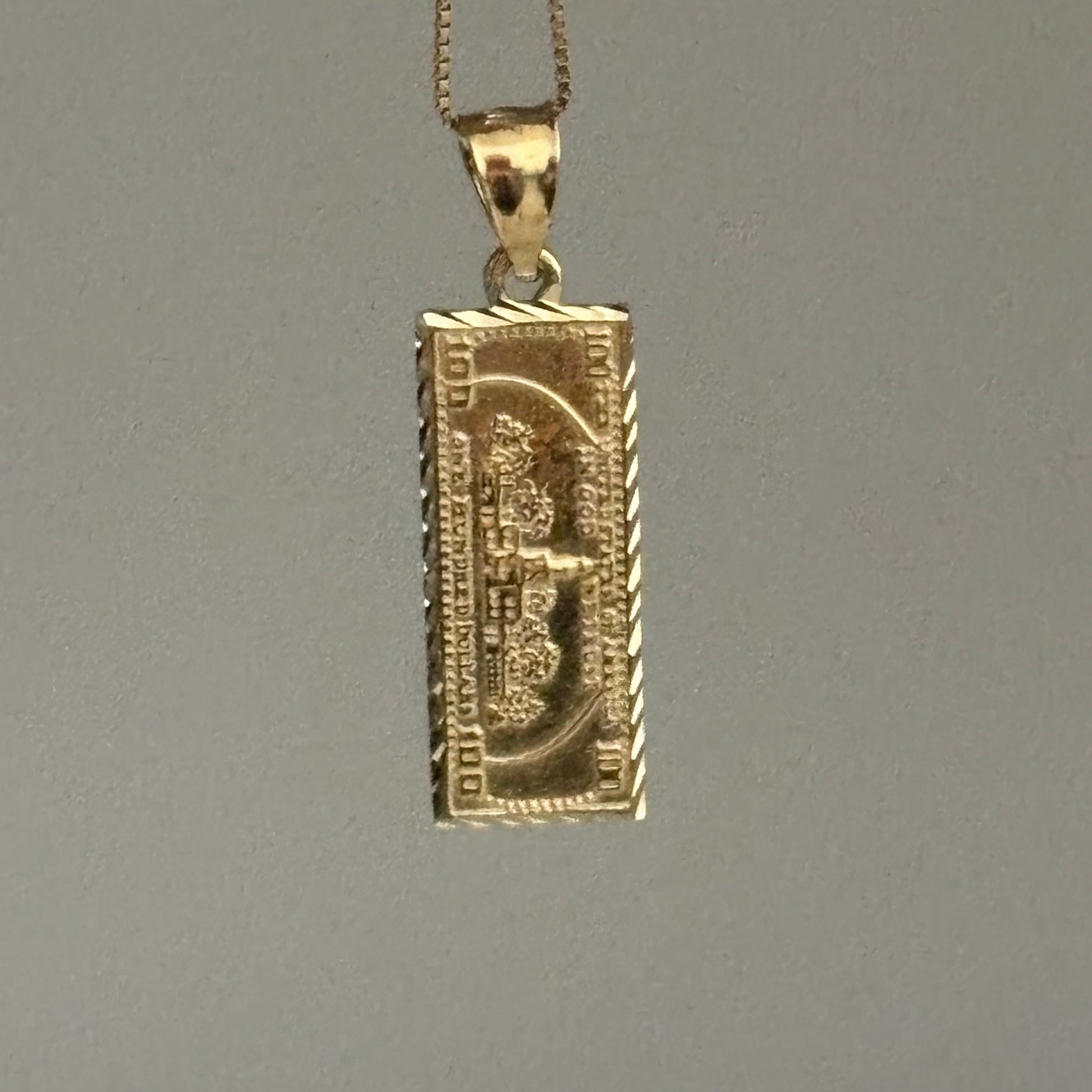 Gold dollar bill pendant on a gray background