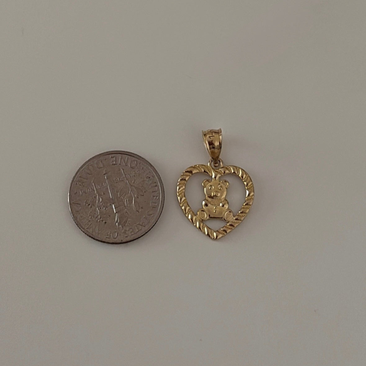 14k gold heart bear charm next to a coin for reference