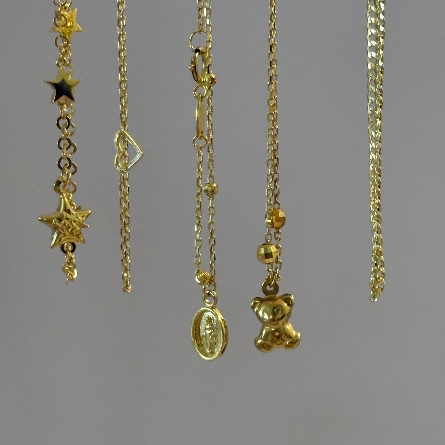 Gold anklets with various designs on a gray background