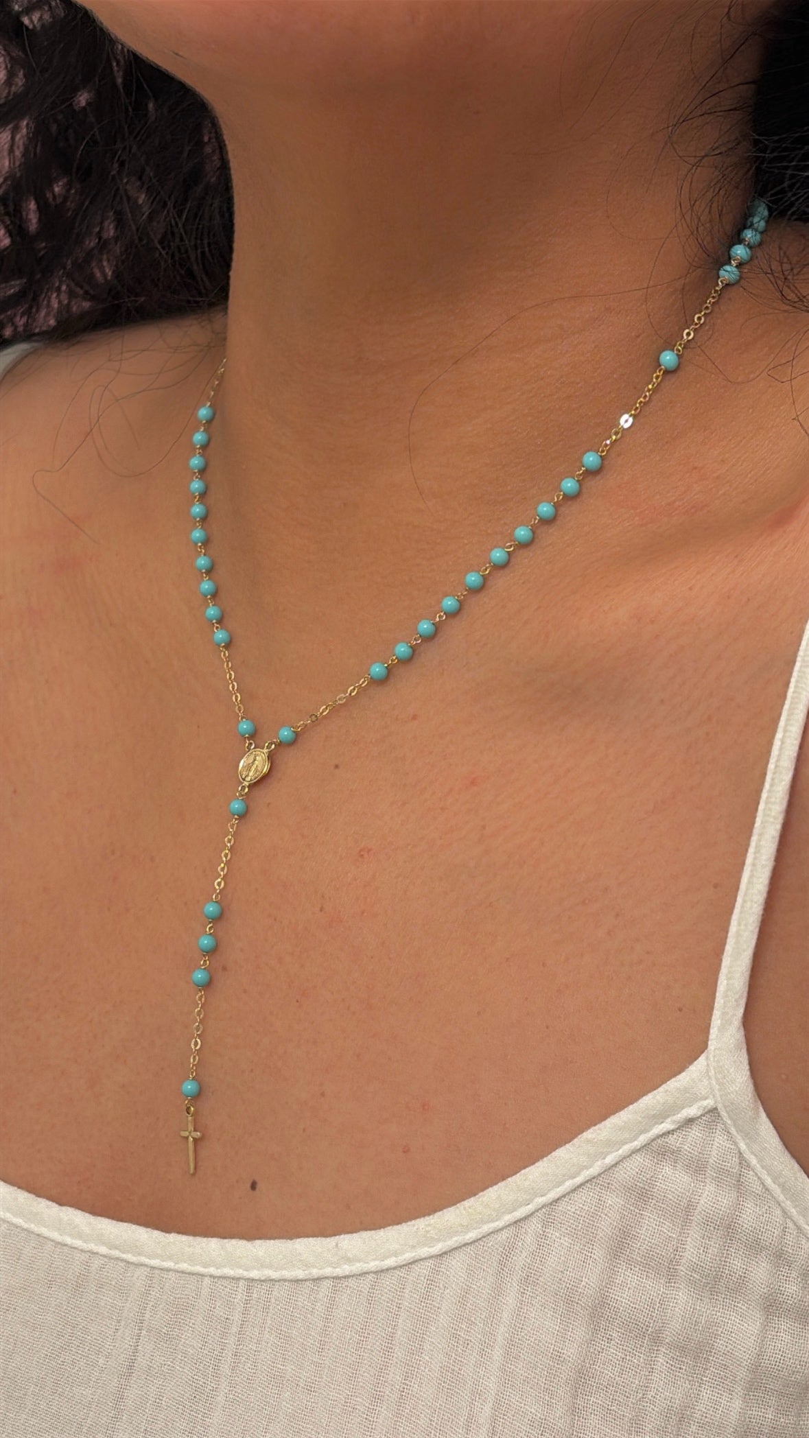 Turquoise beaded necklace with a gold chain worn by a person