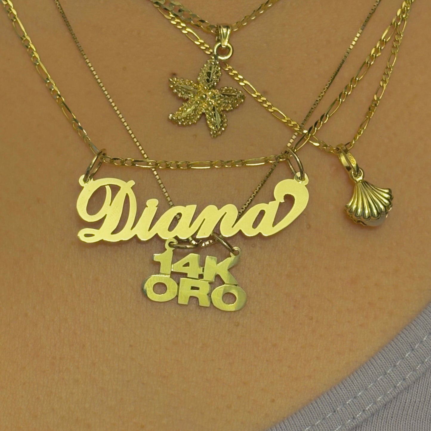 Gold necklaces with 'Diana' and '14K ORO' pendant on a beige background
