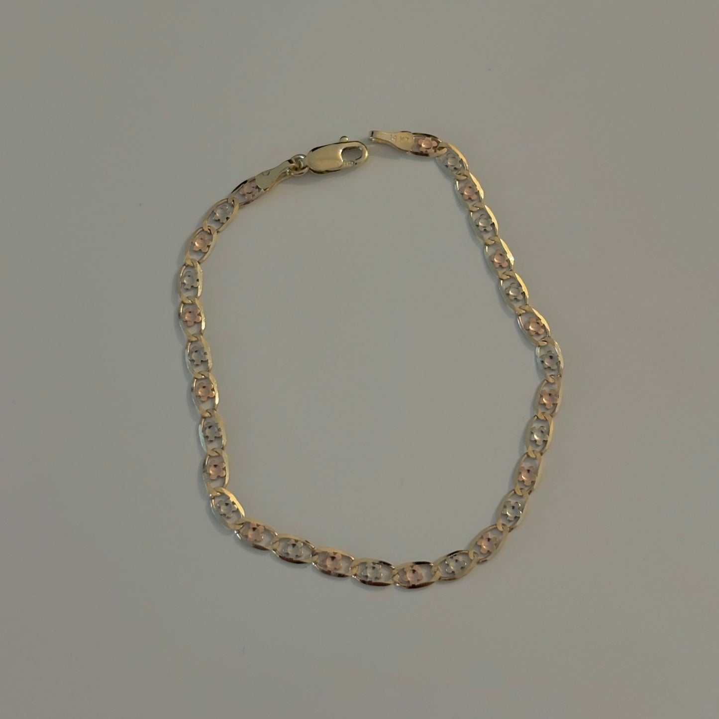 Gold flower chain bracelet on a gray background