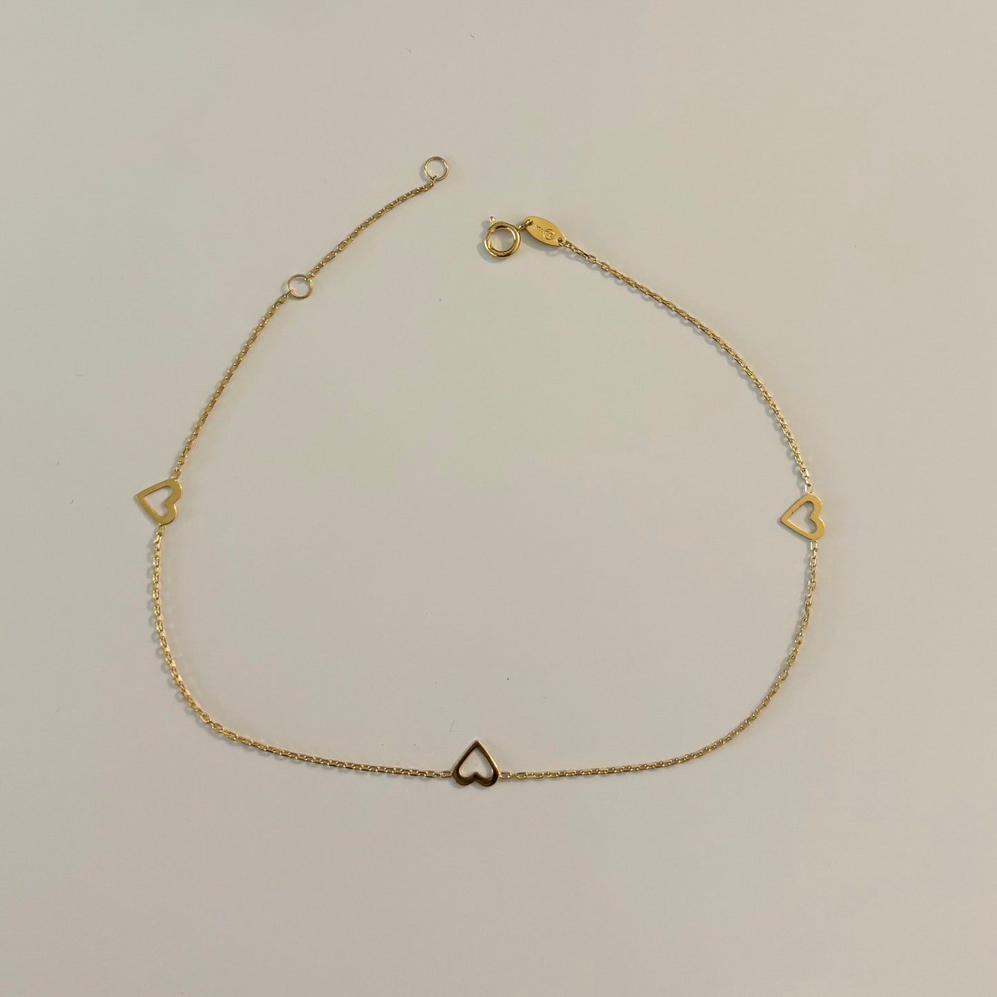Gold necklace with heart-shaped pendants on a white surface