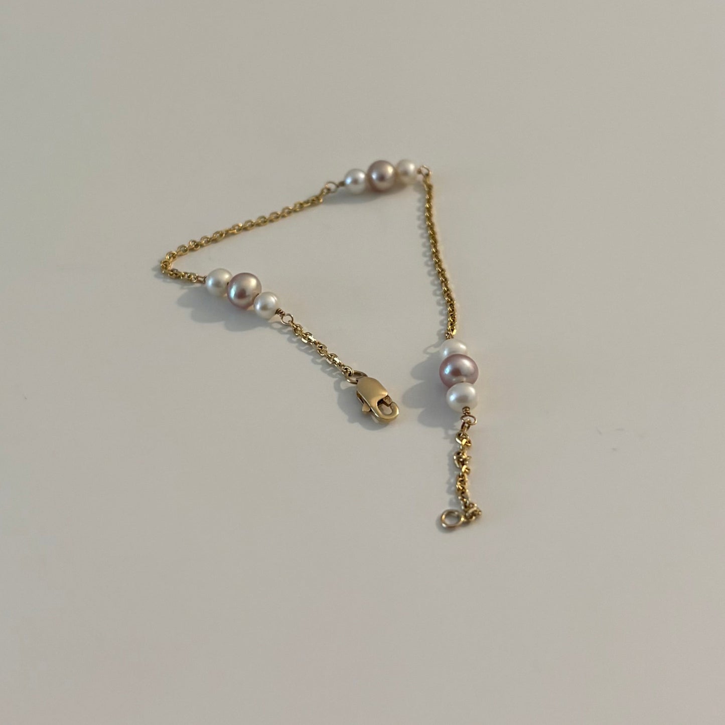 Gold chain with pearls on a white surface