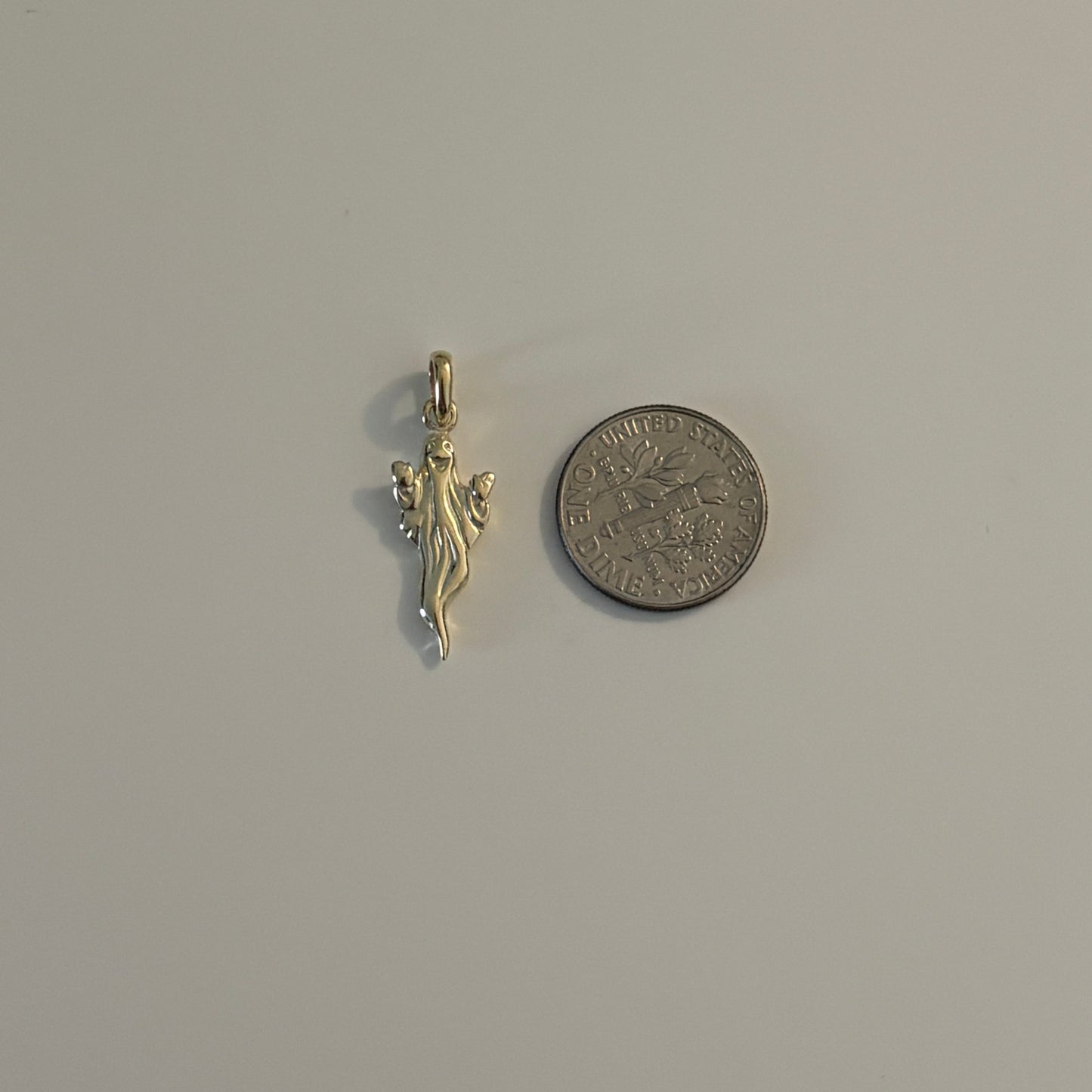 halloween gold ghost charm next to a coin