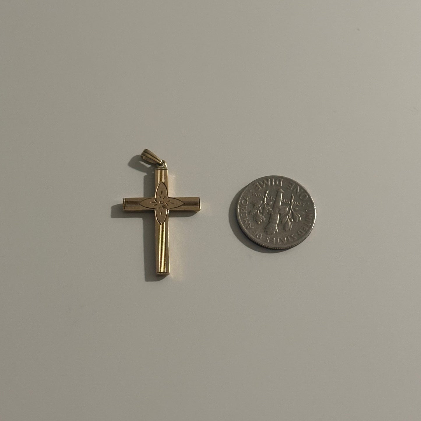Small cross pendant and coin on a light gray background