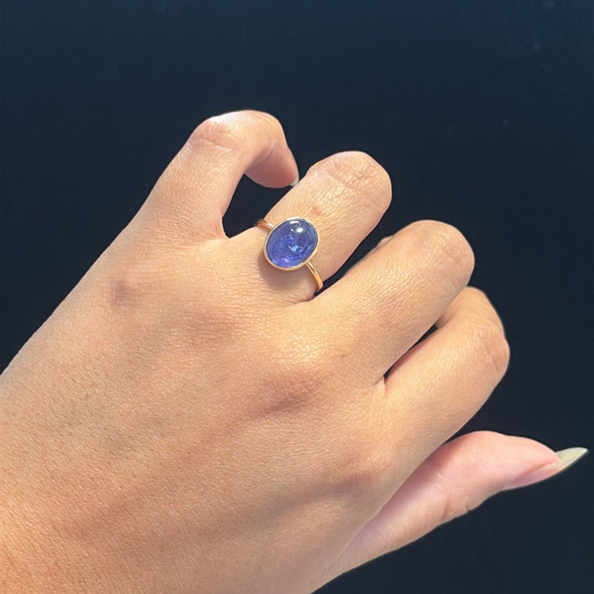 14K gold cabochon tanzanite ring on finger for reference