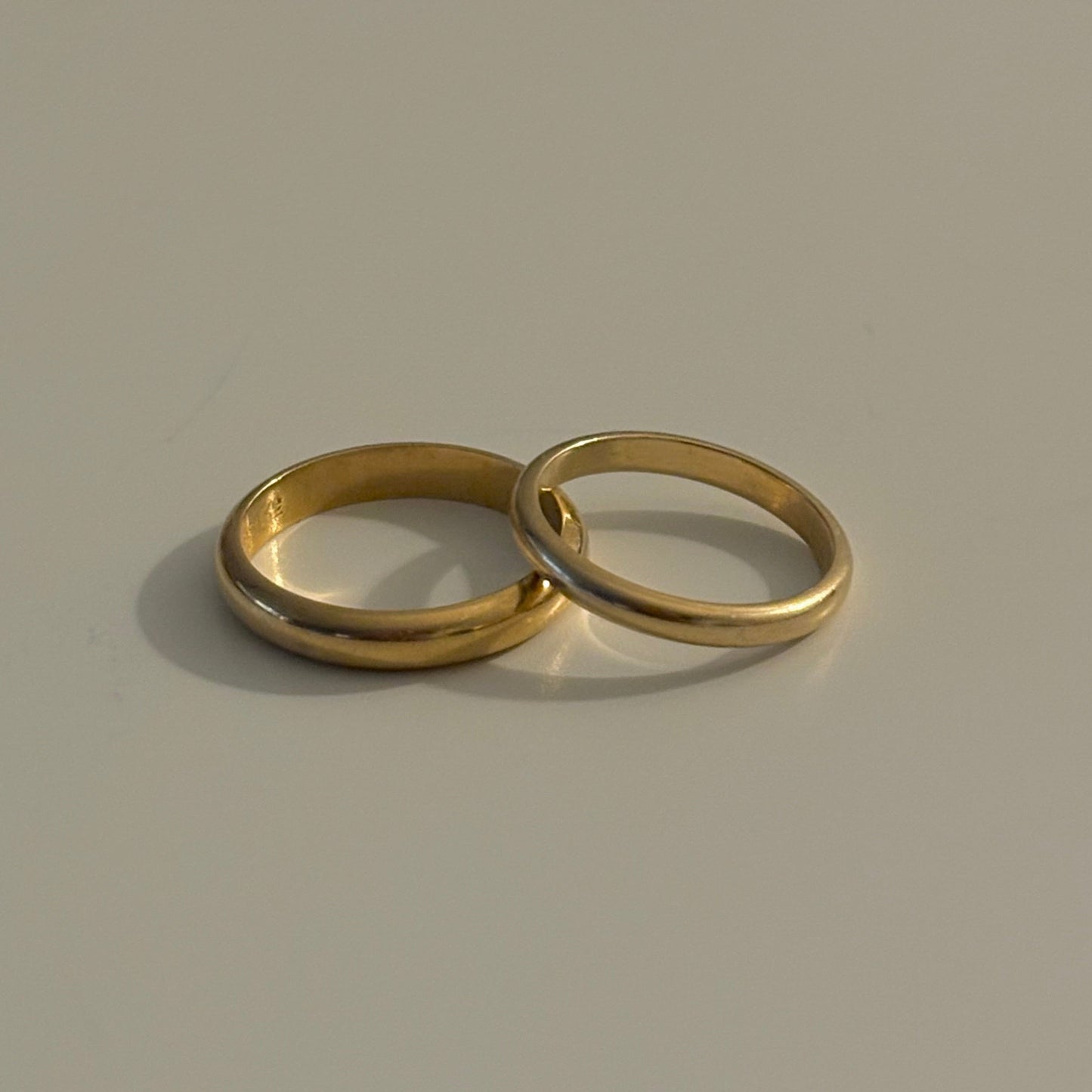 Two gold rings on a beige background