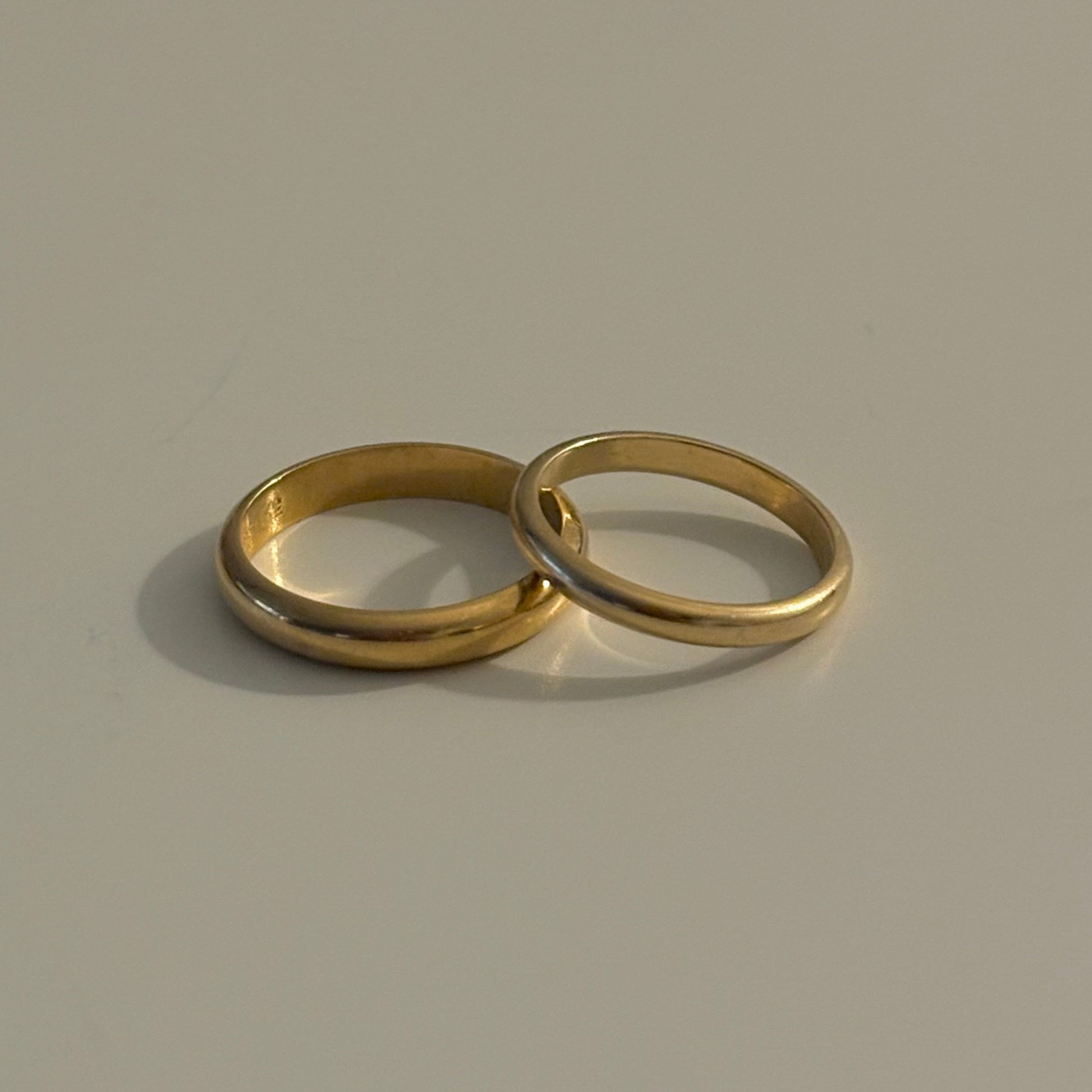 Two gold rings on a beige background