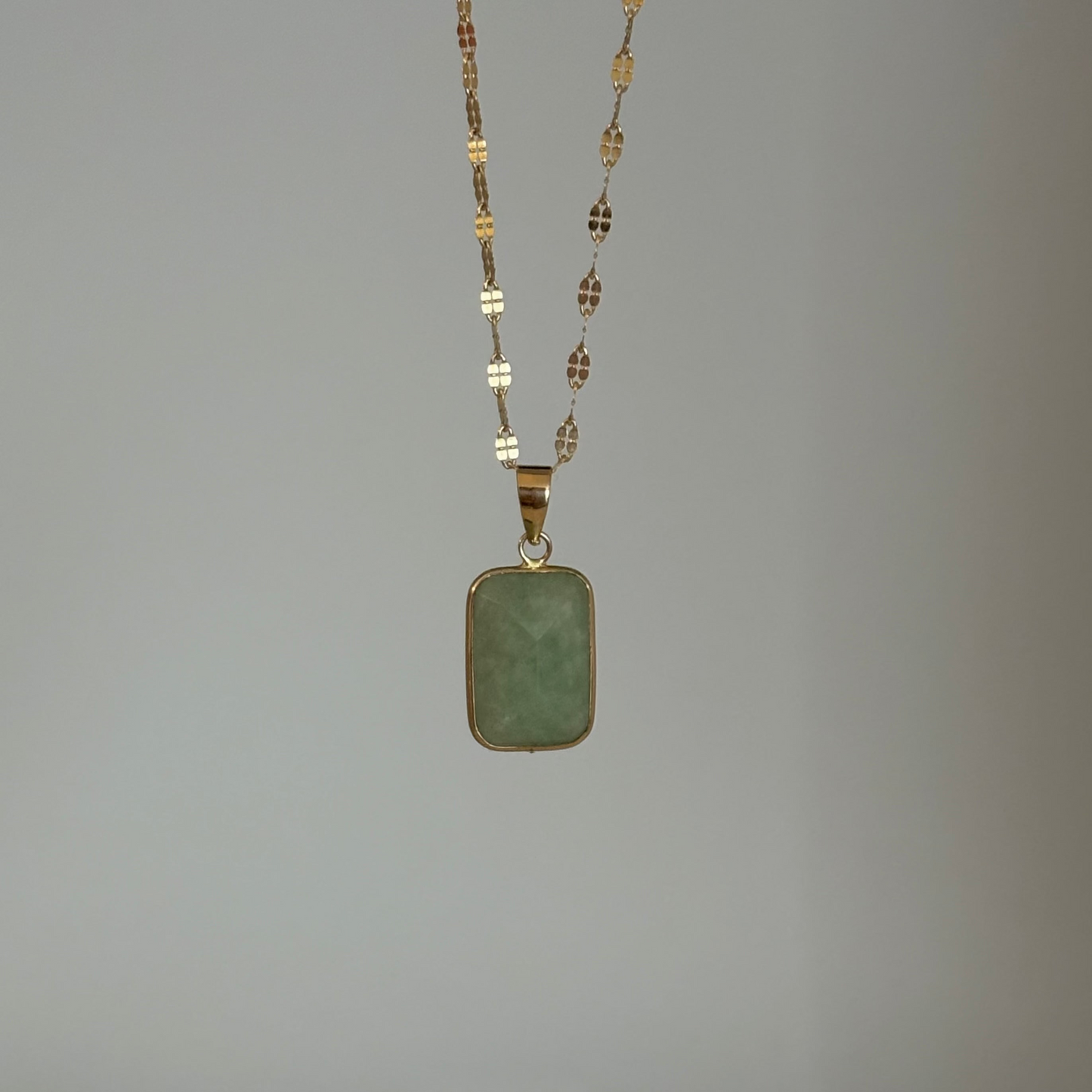 Necklace with a green pendant on a plain background