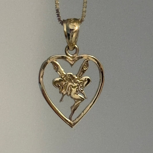 Gold fairy pendant next to a silver coin on a gray background
