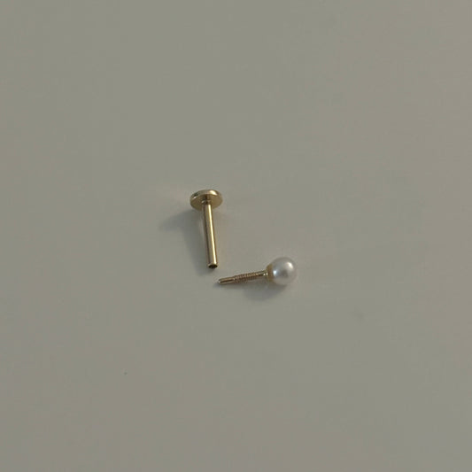 Gold earring with pearl on a light gray background
