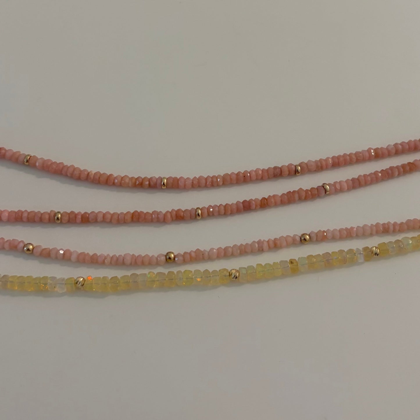 Three beaded bracelets on a white surface with a Hello Kitty branded card in the background.