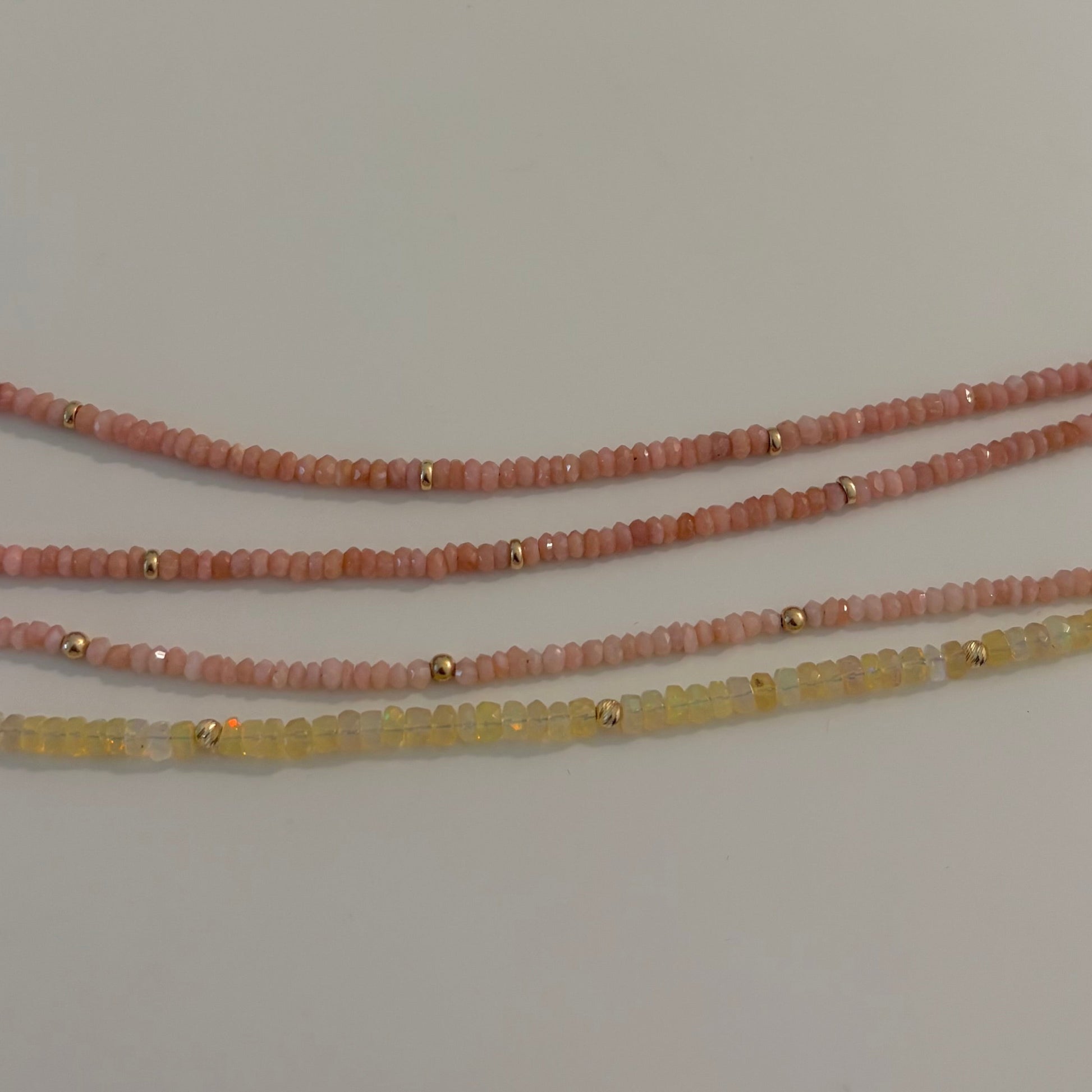 Three beaded bracelets on a white surface with a Hello Kitty branded card in the background.