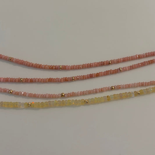 Three beaded bracelets on a white surface with a Hello Kitty branded card in the background.
