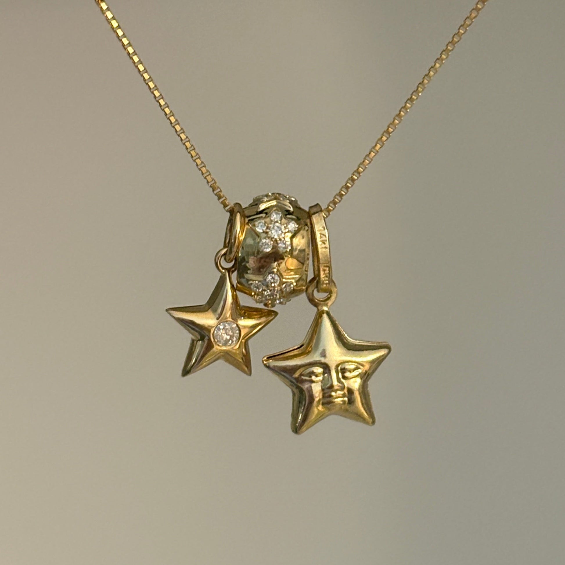 Gold necklace with star-shaped pendants on a neutral background