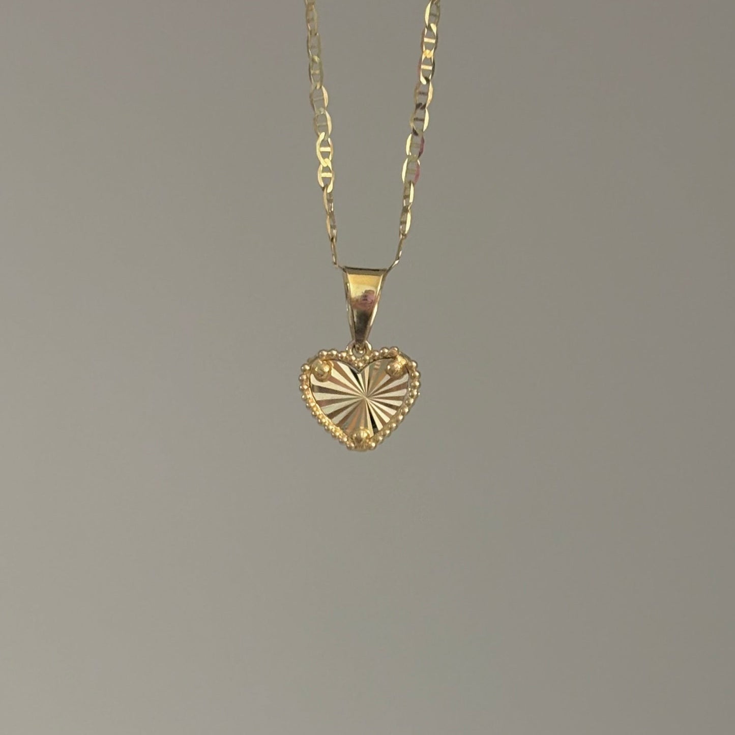 Gold heart-shaped pendant necklace on a gray background