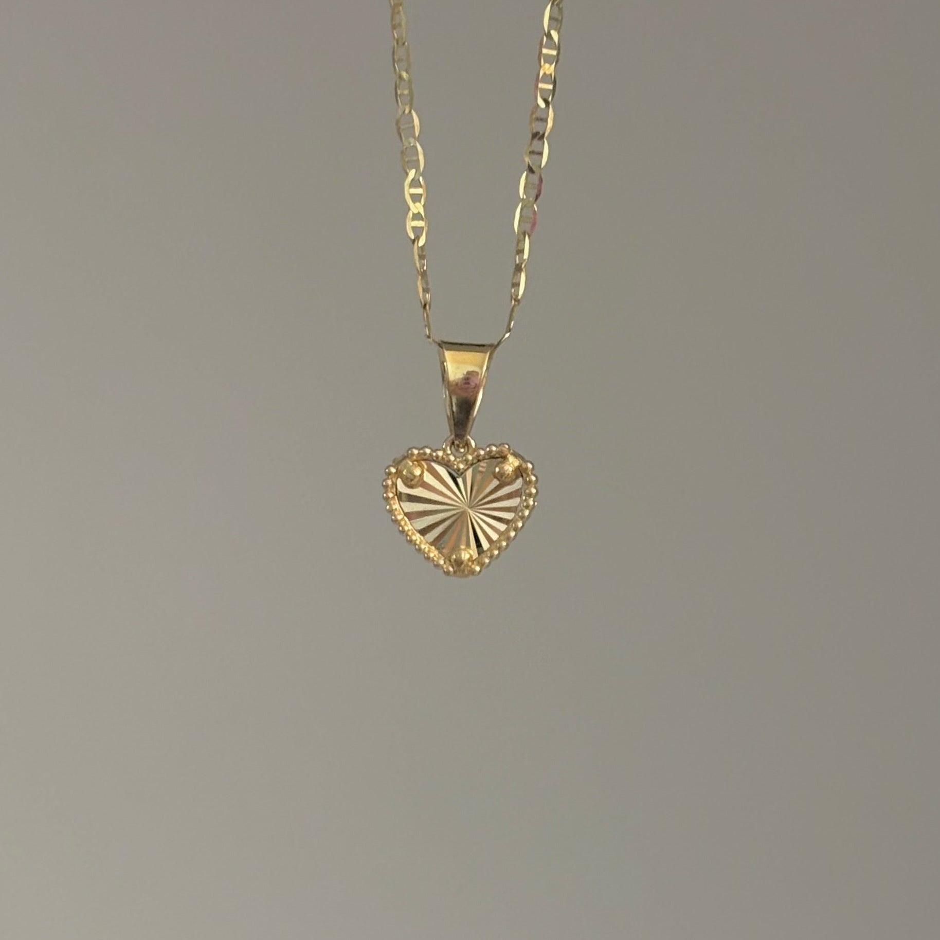 Gold heart-shaped pendant necklace on a gray background