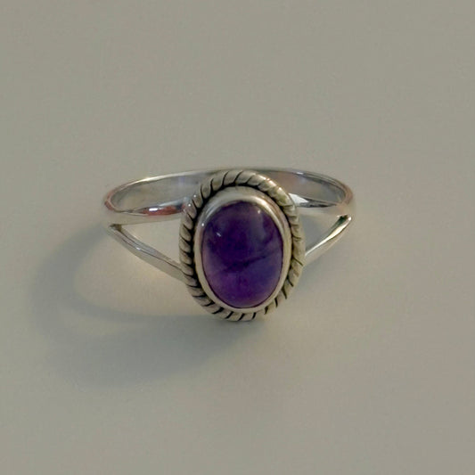 Silver ring with a purple gemstone on a gray background