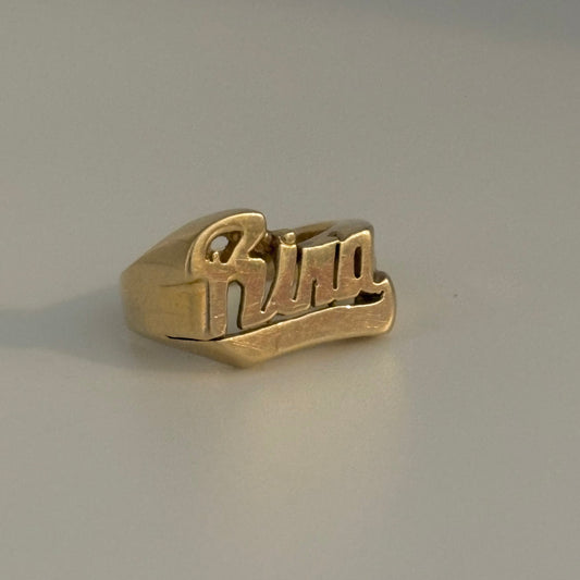 Gold ring with 'Rina' engraving on a gray background