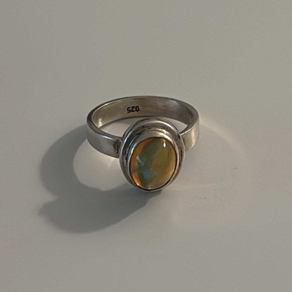Silver ring with a yellow gemstone on a gray background
