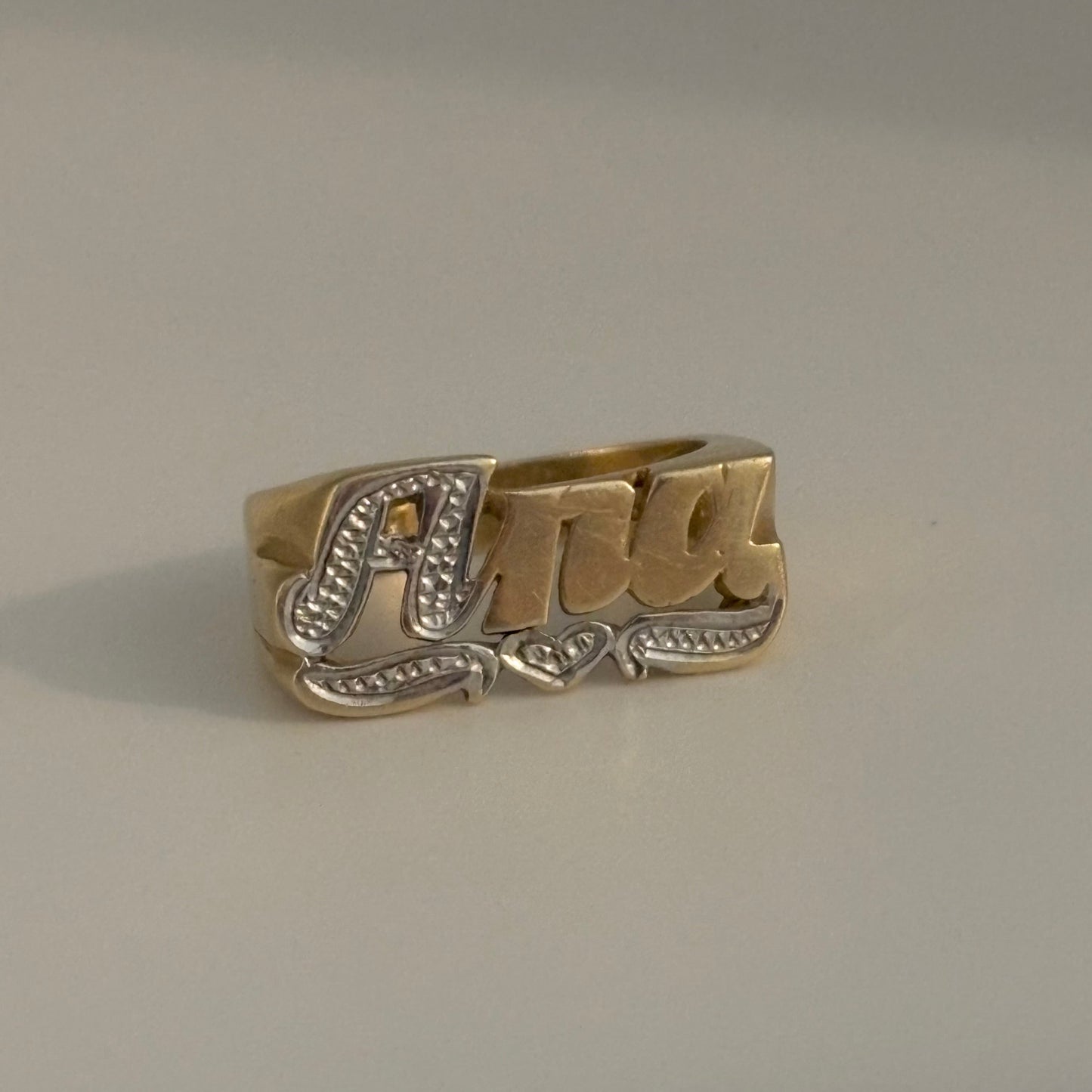 Gold ring with 'Ana' engraving on a gray background