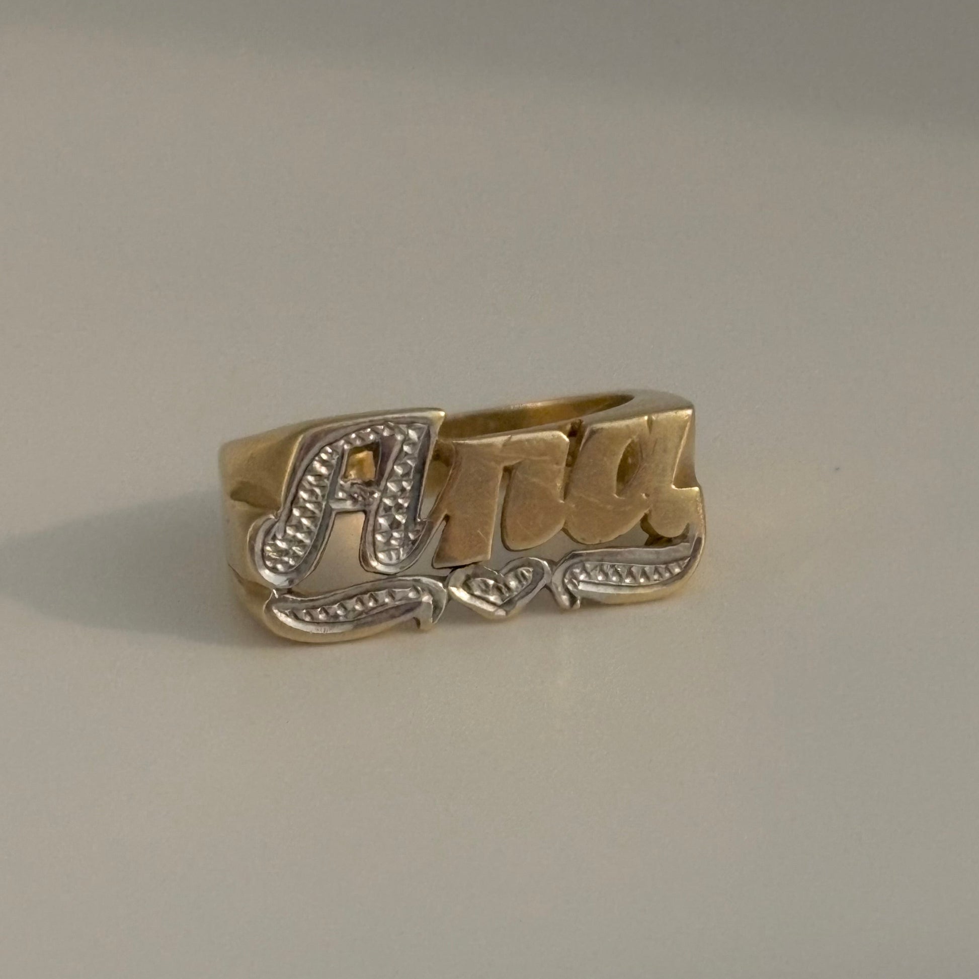 Gold ring with 'Ana' engraving on a gray background