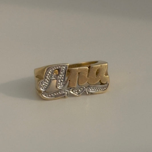 Gold ring with 'Ana' engraving on a gray background