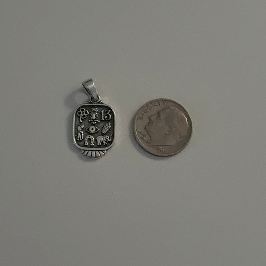 Small silver pendant and coin on a gray background