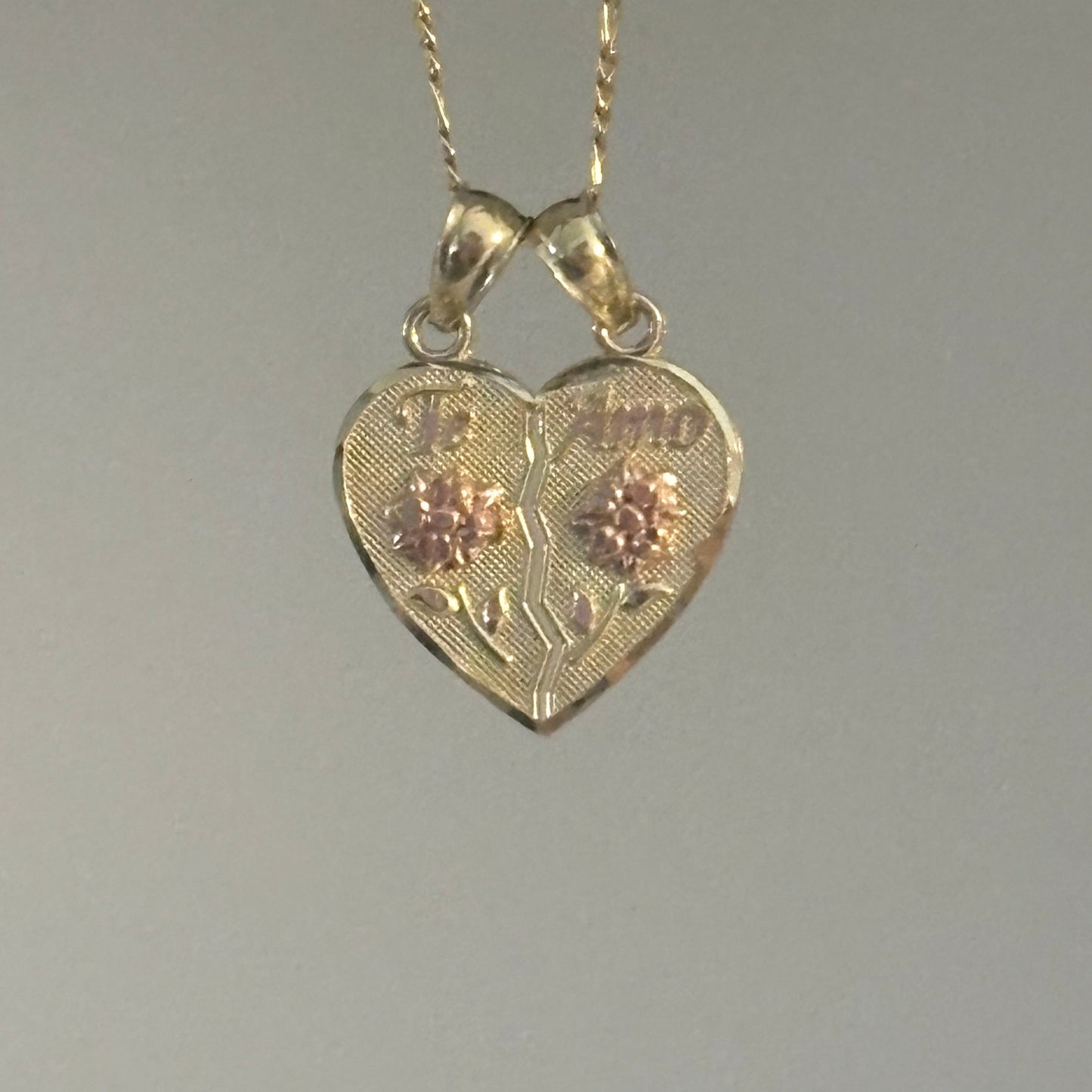 Gold heart-shaped pendant with chain on a gray background