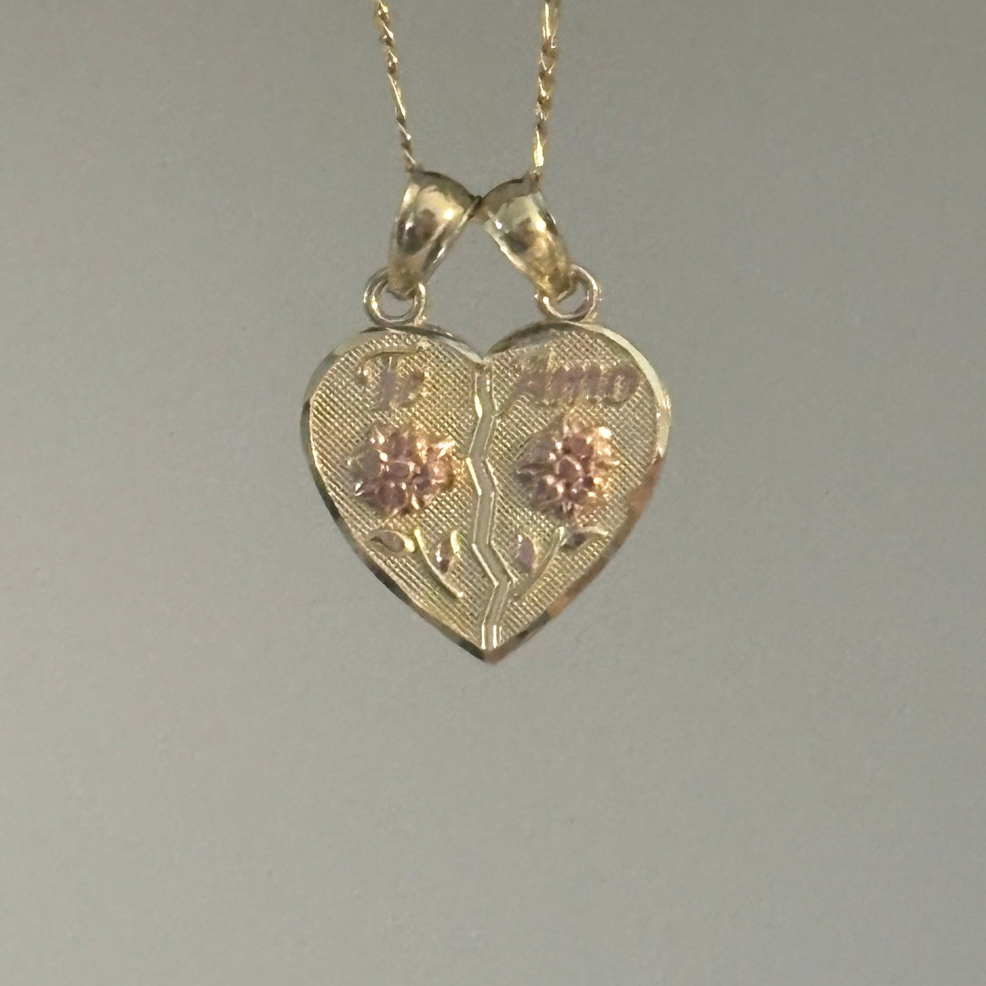 Gold heart-shaped pendant with chain on a gray background