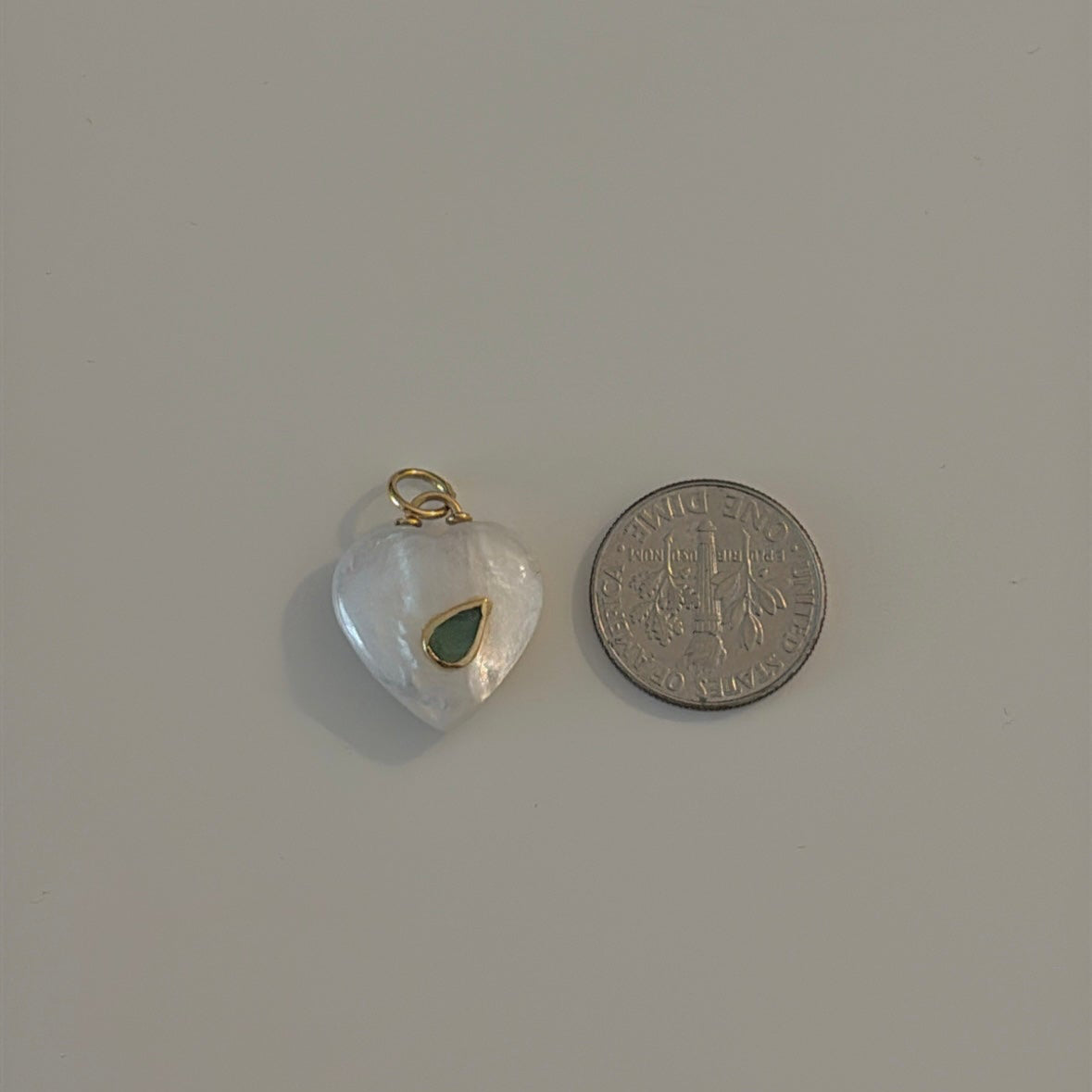 14K gold mother of pearl heart with pear emerald pendant  next to a coin for reference 