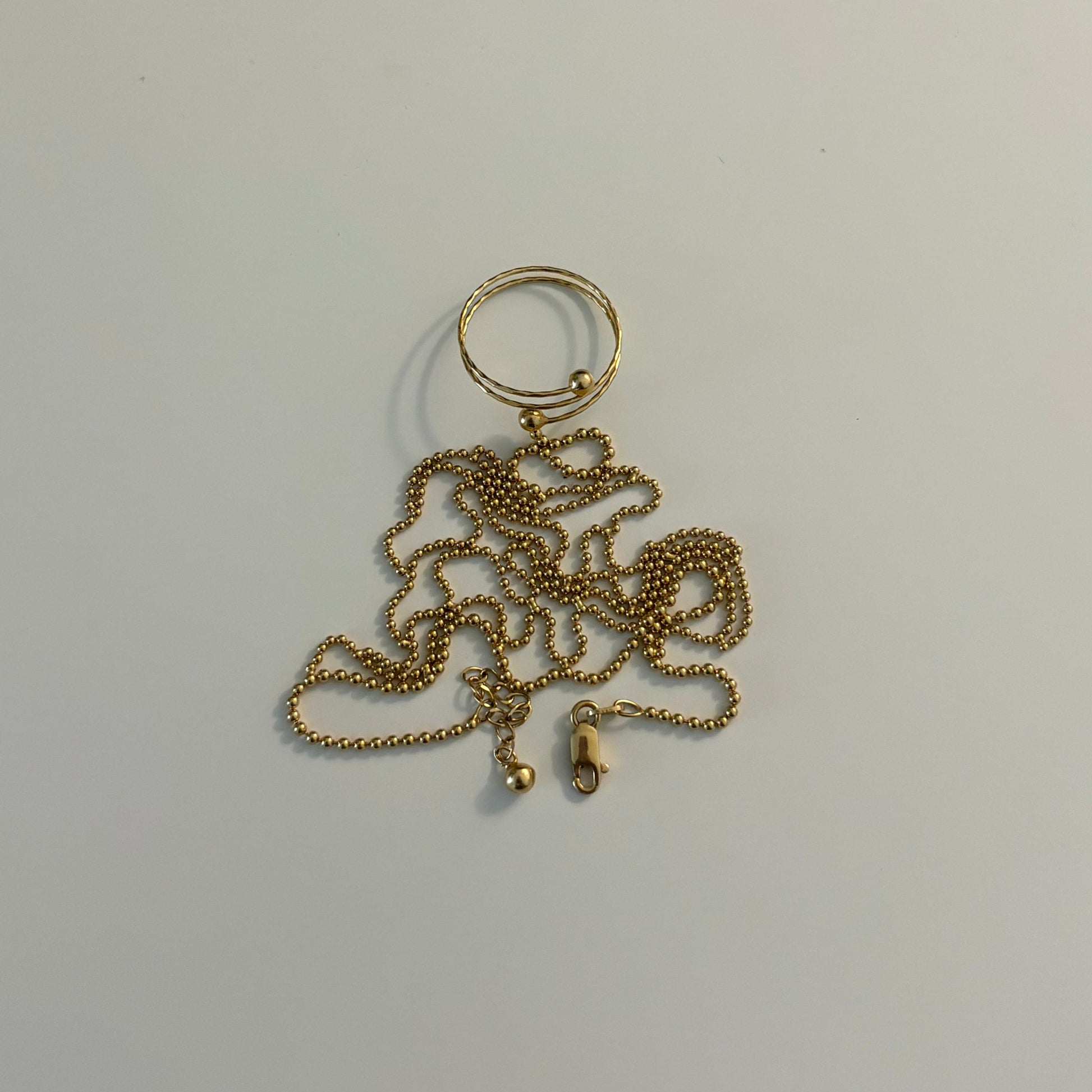Gold chain keychain on a white surface next to a gold electronic device