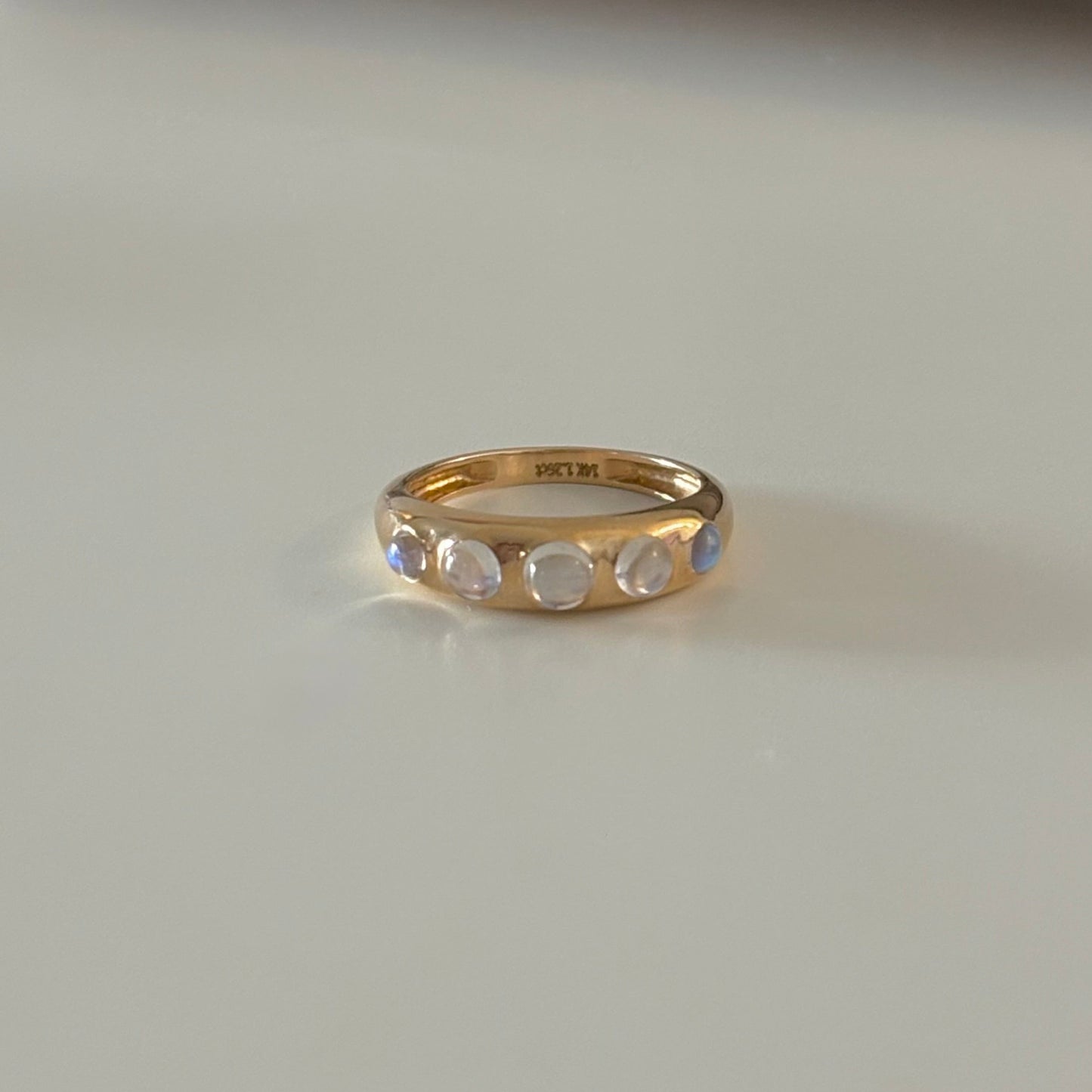 Gold ring with gemstones on a white surface