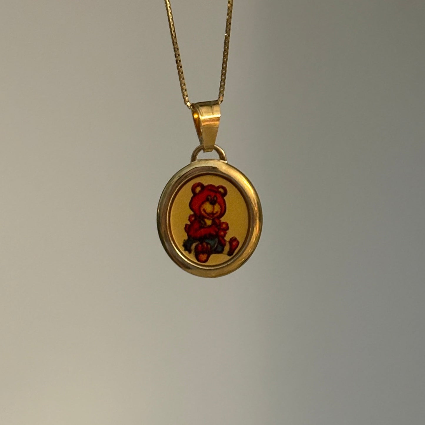 Gold necklace with a round pendant on a gray background