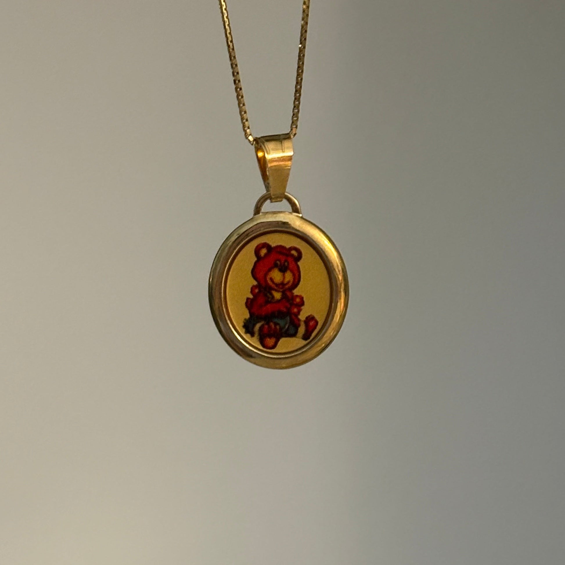 Gold necklace with a round pendant on a gray background