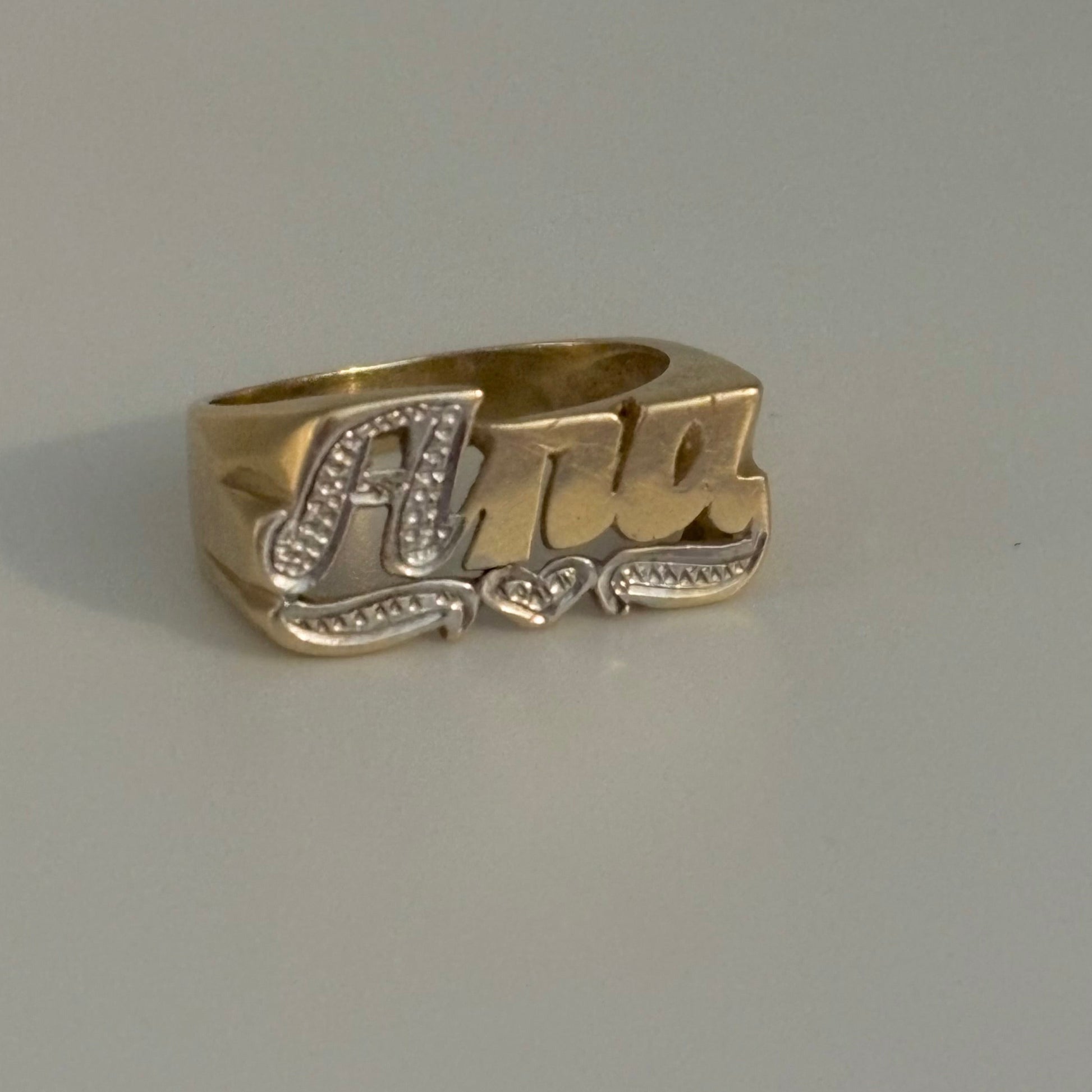 Gold ring with 'Ana' engraving on a gray background