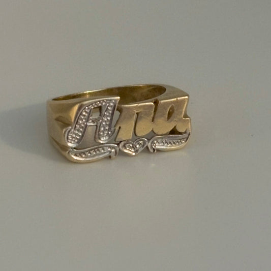 Gold ring with 'Ana' engraving on a gray background