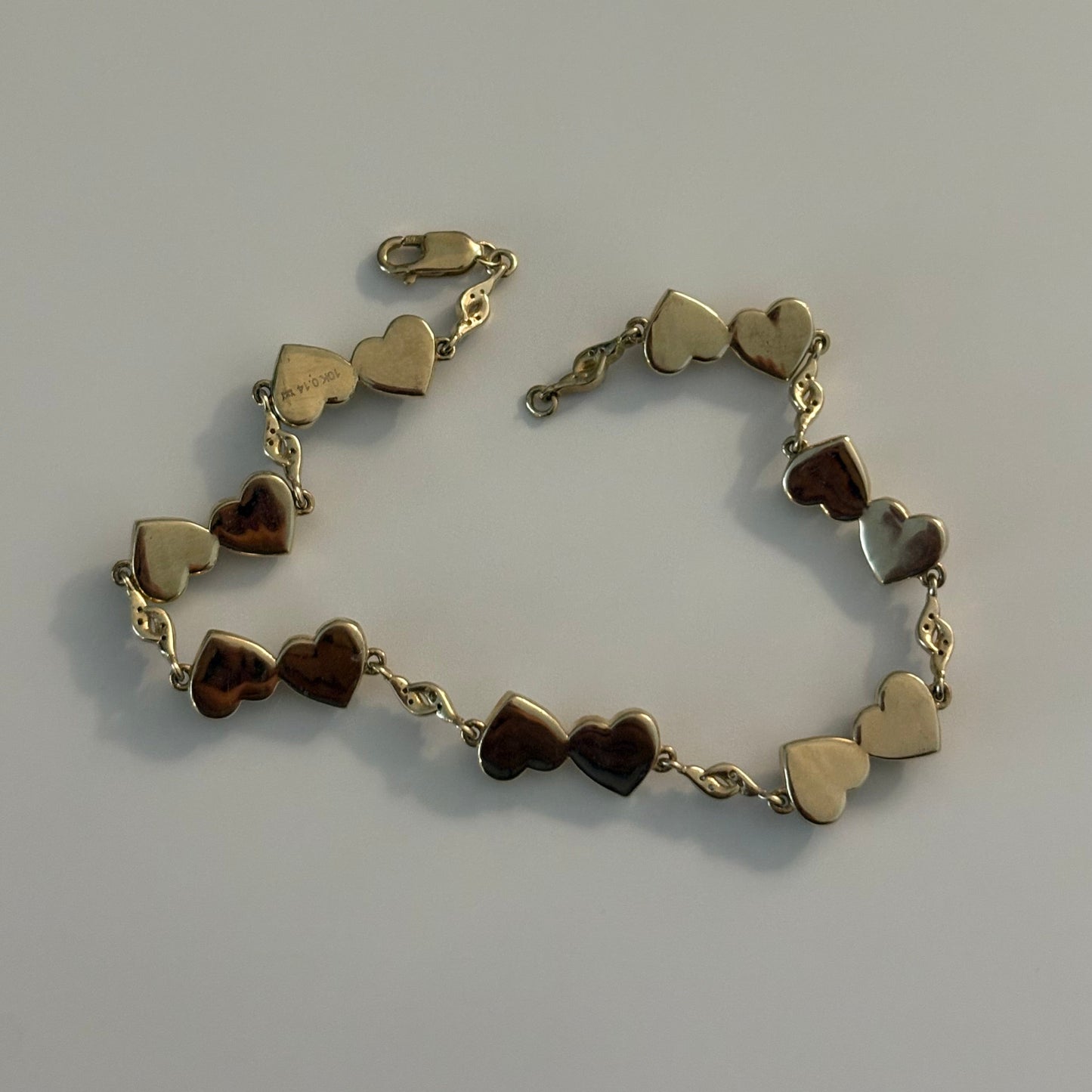 Gold bracelet with heart-shaped charms on a gray background