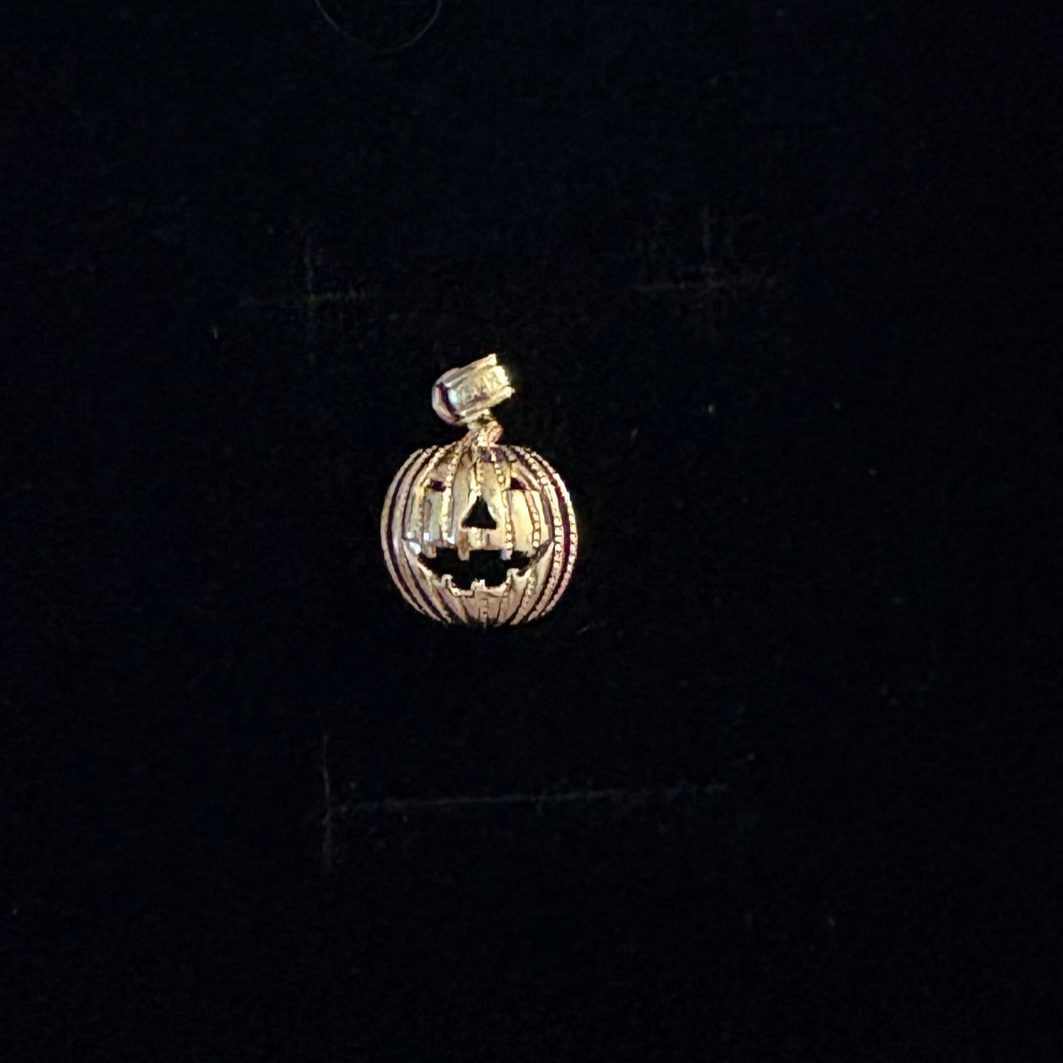 14K gold pumpkin charm with jack-o’-lantern face, Halloween pendant on black background