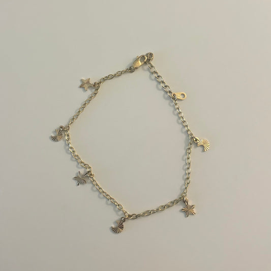 Gold bracelet with star and cross designs on a light gray surface.