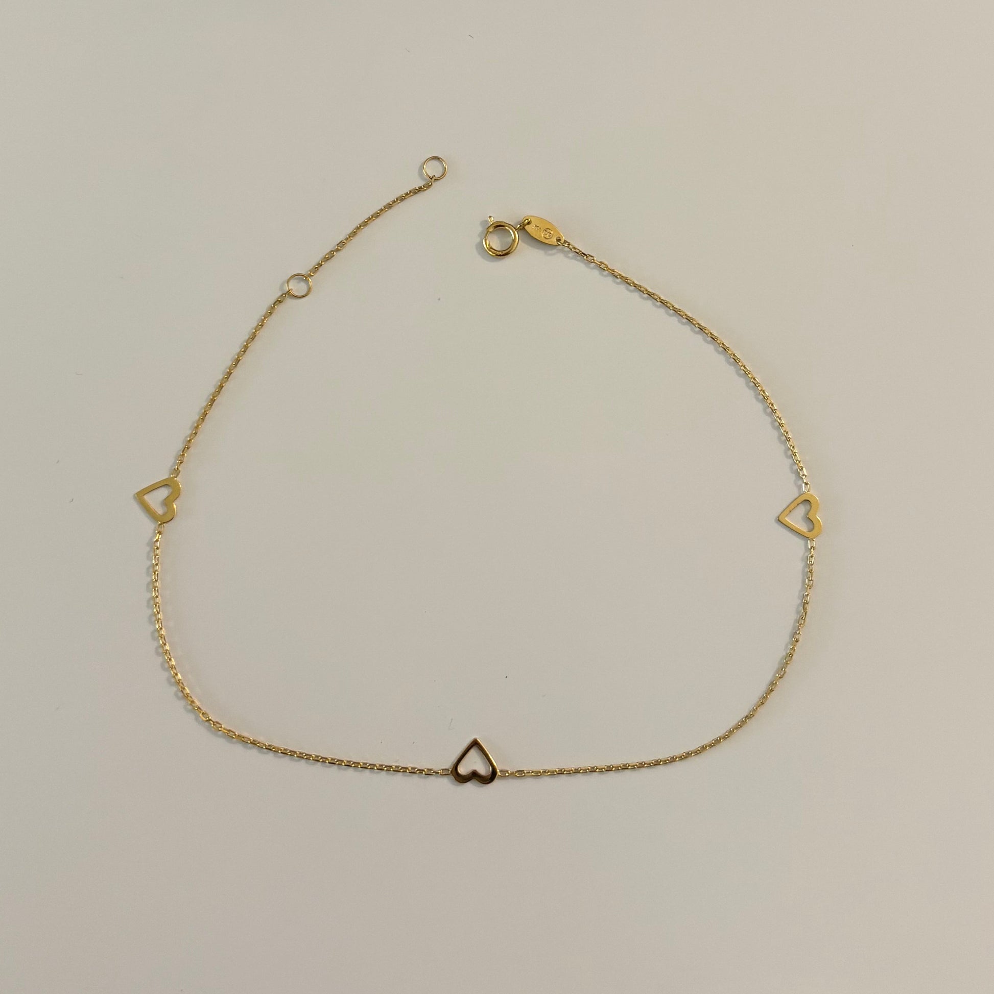 Gold necklace with heart-shaped pendants on a white surface