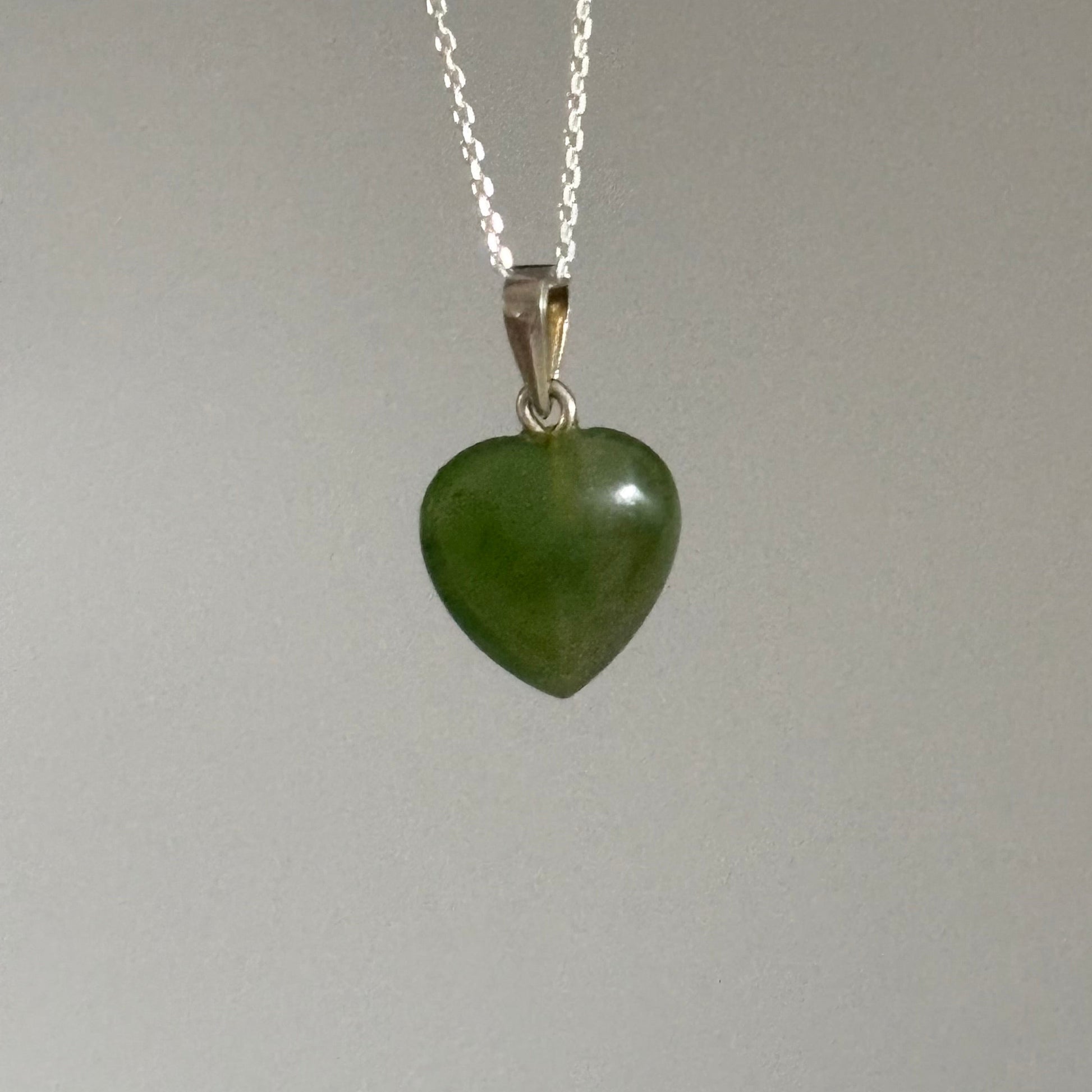 Necklace with a green heart-shaped pendant on a plain background